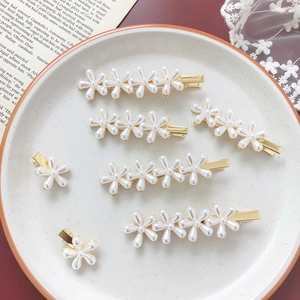 Detailed view of pearl flower hair clips in a ceramic dish with vintage background