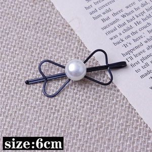 Détail d'une barrette nœud noir avec perle, montrant la taille du produit de 6cm