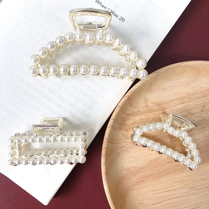 Detailed view of elegant gold metal hair claws with inlaid white pearls in geometric shapes