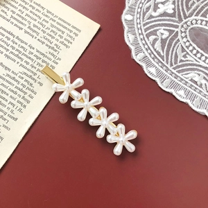 Detailed macro view of retro gold flower hair clip with pearls on a vintage background