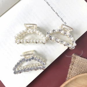 Detailed view of three luxury gold-tone hair claws with pearls and rhinestones