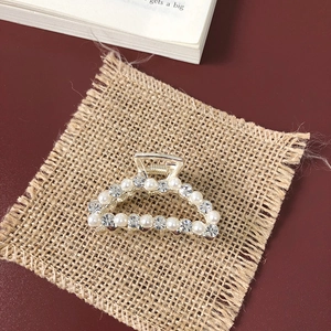 Close-up of golden hair claw with white pearls and sparkling rhinestones on fabric