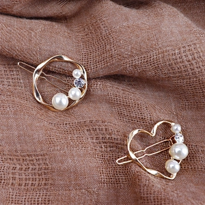 Set di fermagli per capelli dorati con perle e strass su sfondo di tessuto strutturato
