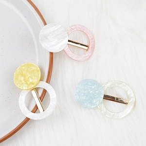 Détail de barrettes rondes en acétate aux couleurs bonbon sur fond en peluche