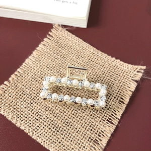 Detail shot of golden metal hair claw with inlaid pearls and sparkling rhinestones