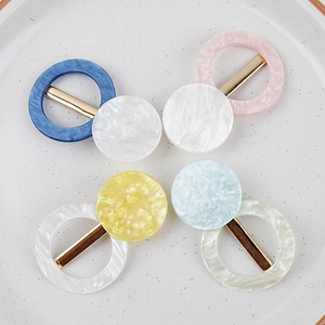 Pinces à cheveux en résine marbrée aux couleurs pastel disposées sur un plateau en céramique