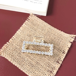 Detail of luxury gold hair claw clip with rows of sparkling rhinestones on linen fabric