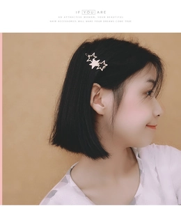 Close-up of a triple star gold metal hair pin with black enamel on a model side profile