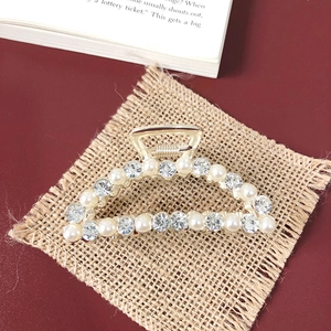 Close-up of golden hair claw clip with luxurious pearls and rhinestones on linen fabric