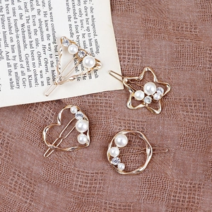 Dettaglio di quattro fermagli dorati con perle e strass su una pagina di un libro d'epoca