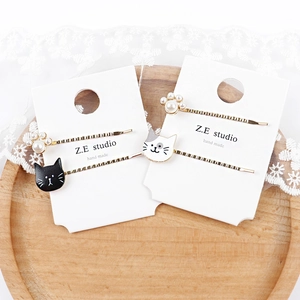 Nahaufnahme goldener Katzen-Haarspangen mit Perlenpfoten und Emaille-Designs