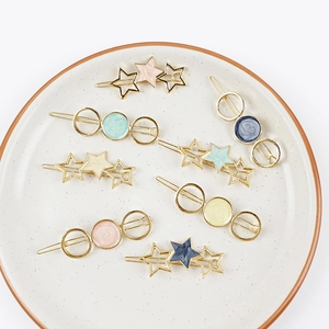 Close-up of golden alloy star and round hair clips with marble texture drip oil inlay