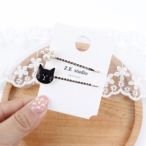 Detailansicht der Perlen-Katzenpfote und schwarzen Emaille-Haarspangen in der Hand