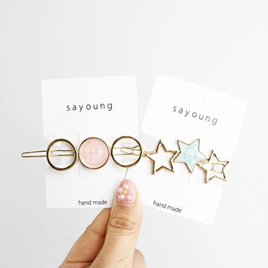 Close-up of pastel pink and mint green star-shaped hair clips on a white display card