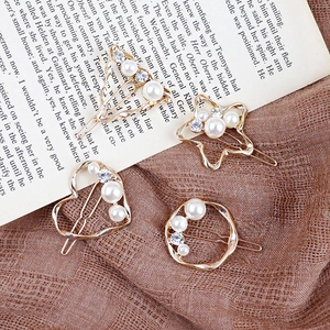 Set di quattro fermagli dorati geometrici con perle e strass su sfondo in stile vintage