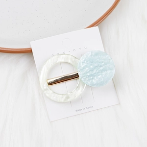 Détail d'une barrette en acrylique marbré bleu aux formes circulaires et métal doré