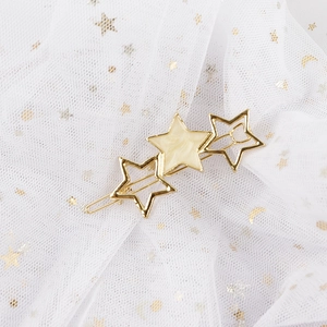 Detail of golden star hair clip with marble texture on shiny star-patterned mesh base