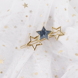 Detailed close-up of a star-shaped hair clip with gold finish and grey marble inlay