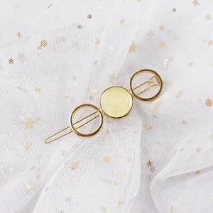 Detail of a gold alloy hair clip with circular resin texture on star mesh background
