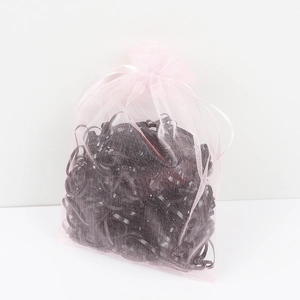 Detailed view of black elastic hair ties stored in a pink organza drawstring bag