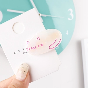 Detailed close-up of a cute milky white acetate cat hair clip with pink engraved outlines