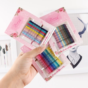 Set of colorful wave-shaped bobby pins on pink cards for stylish hair styling