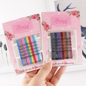 Set of colorful wavy metal hairpins in candy and vintage tones held by hand