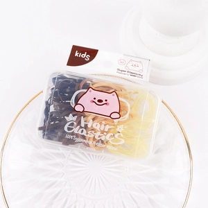 Detailed view of colorful elastic hair ties in a transparent box on a gold-rimmed plate
