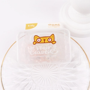 Close-up of kids hair ties set in a cat-themed storage box on a gold-rimmed white tray