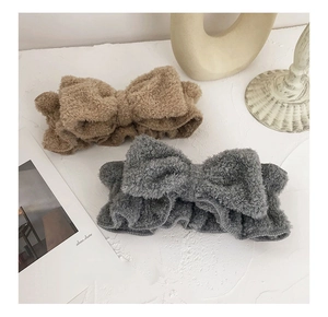 Macro view of plush khaki and grey bowtie headbands on a minimalist white surface