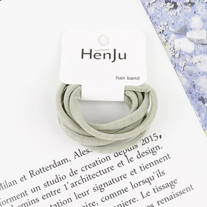 Detail of high-elasticity hair bands in soft sage green on white brand display card