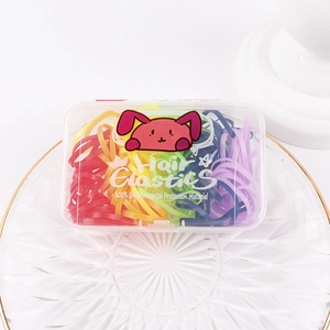 Close-up of colorful elastic hair ties in a clear box on a decorative glass plate
