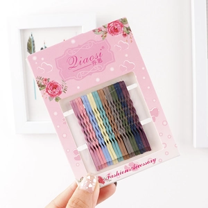 Close-up of colorful wavy bobby pins in various pastel shades on floral card packaging