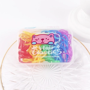 Detail view of colorful hair elastics in a cute pink bear box for kids' hairstyles