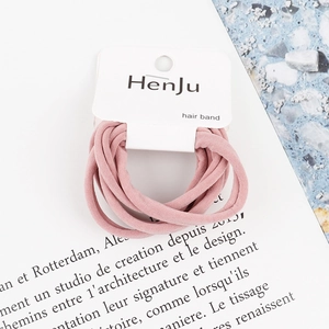 Detail view of pink elastic hair bands on a white branded card with fabric texture