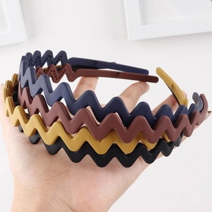 Close-up of four matte wavy headbands in black, yellow, brown, and navy blue