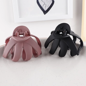 Close-up of matte octopus hair claws in pink and black on a ceramic tray display