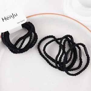 Detail of black braided hair ties on a ceramic tray showing elastic spiral texture