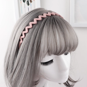 Detail view of a matte pink wavy headband with anti-slip teeth on a model's head