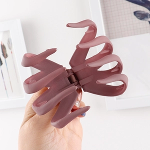 Close-up of matte dusty pink hair claw clip held in hand showing large size and texture