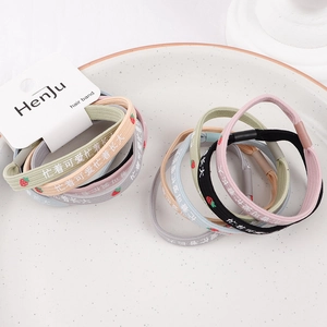 Close-up of colorful braided hair ties with strawberry prints in a ceramic dish