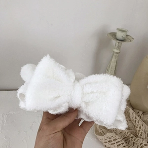 Macro view of white coral fleece headband with soft texture and bowknot detail