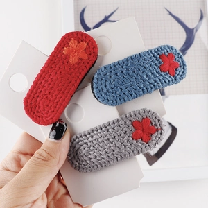 Drei minimalistische handgestrickte Blumen-Haarspangen in Rot, Blau und Grau