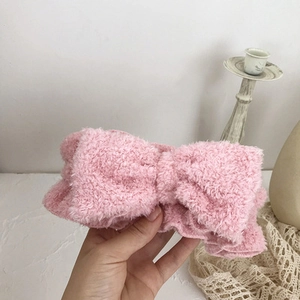 Close-up of soft pink plush bow headband for face washing and skincare routines