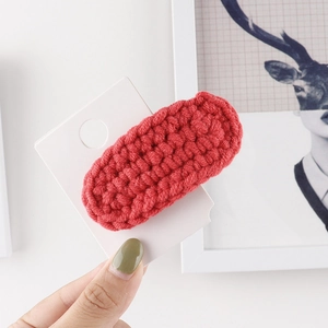 Close-up of red hand-woven thick yarn hair clip showing detailed crochet texture and pattern