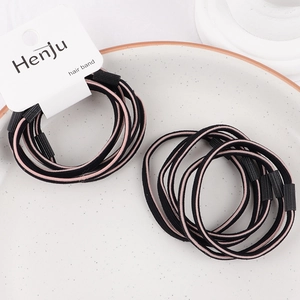 Detail view of pink and black braided elastic hair bands displayed on a ceramic tray