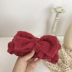 Detailed view of a soft burgundy fleece headband with a large bow for face washing
