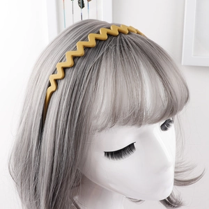 Detail of a bright mustard yellow wavy headband with matte finish on silver hair