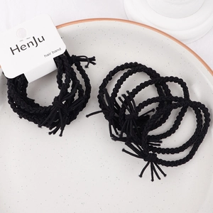 Close-up of black braided elastic hair bands with fine texture on a white tray