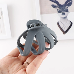 Handheld view of a dusty purple matte octopus hair claw clip for long hair styling